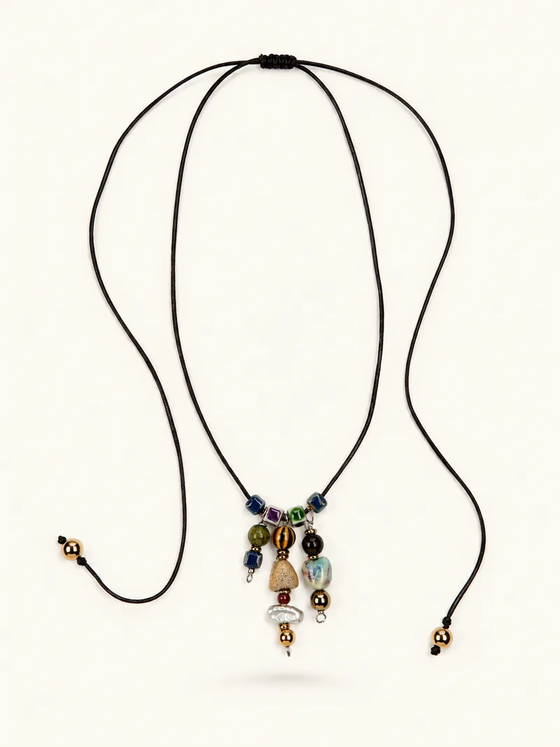 Totem — Coral fósil, perla barroca, cerámica esmaltada, hematita y latón dorado sobre piel, joyería artesanal Meissen Mia